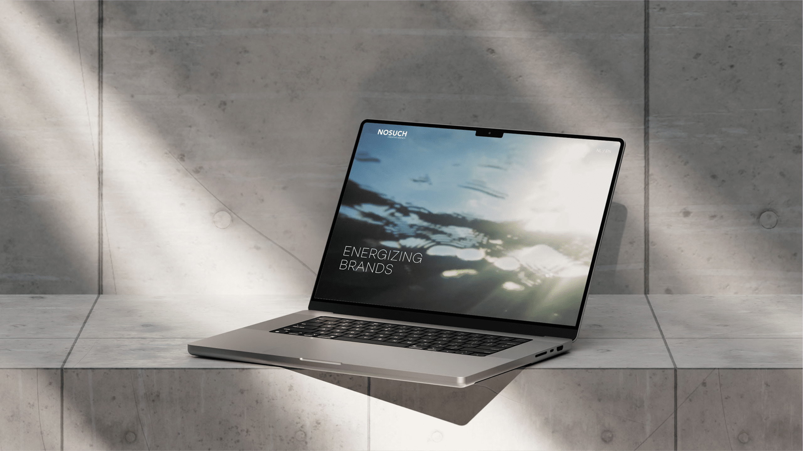 Laptop on concrete surface displaying Energizing Brands screen with abstract light reflections.